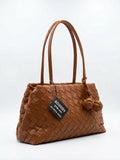A braided bag with a modern design and a knotted pendant