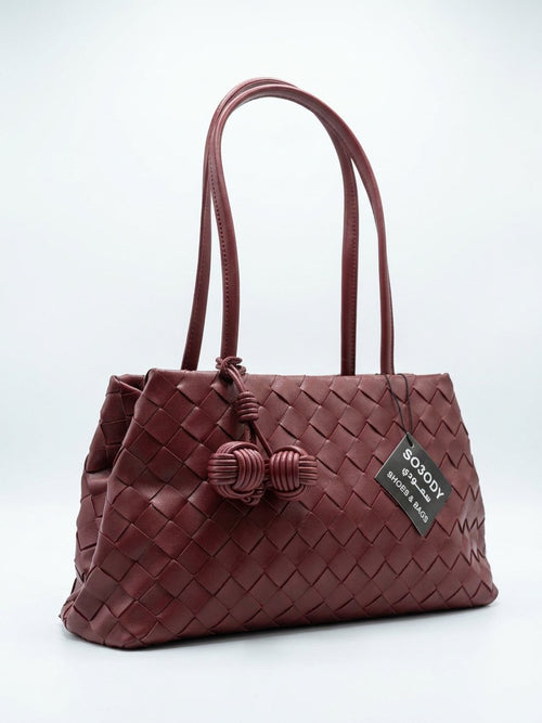 A braided bag with a modern design and a knotted pendant